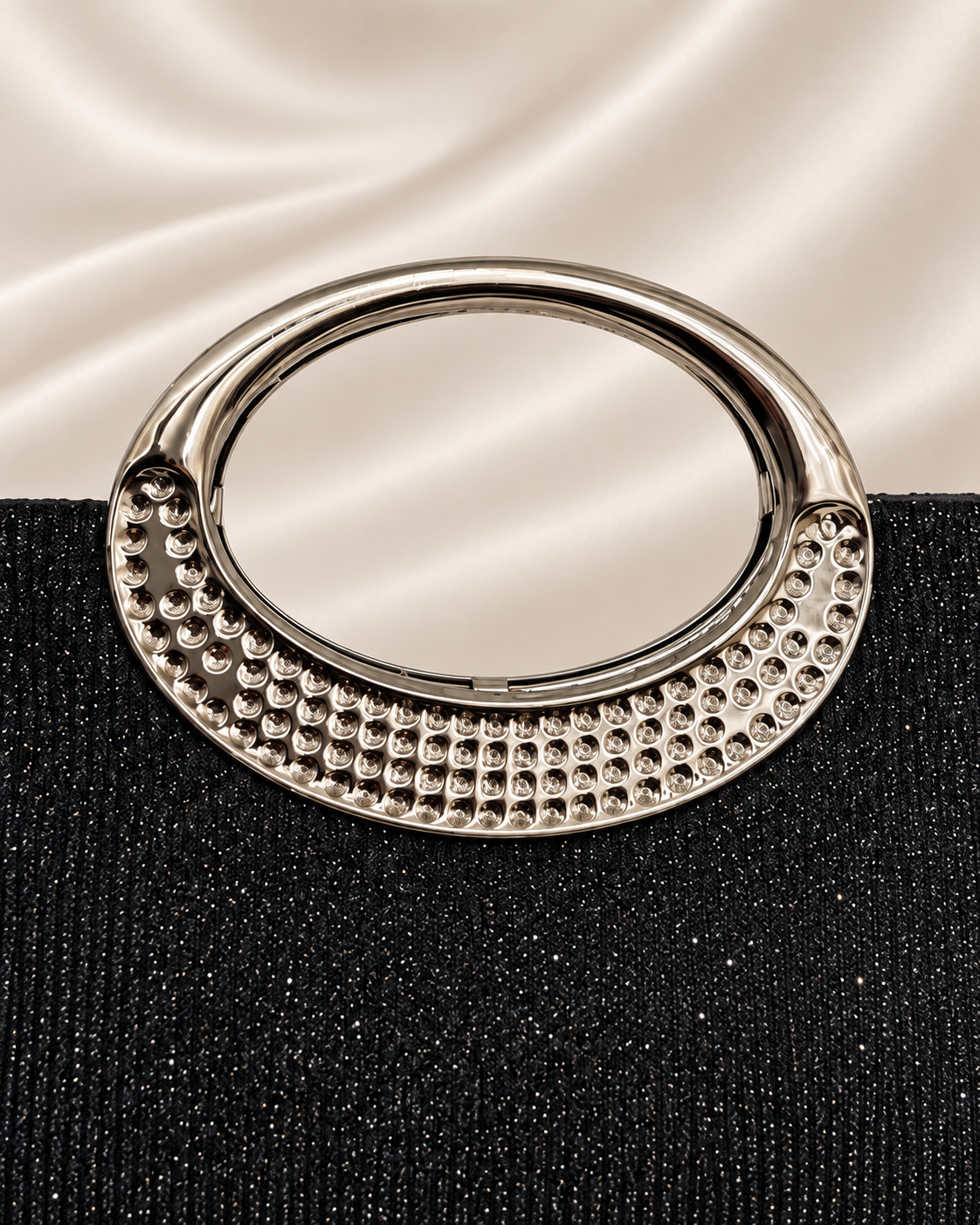 Close-up of silver oval handle on black glitter evening bag
