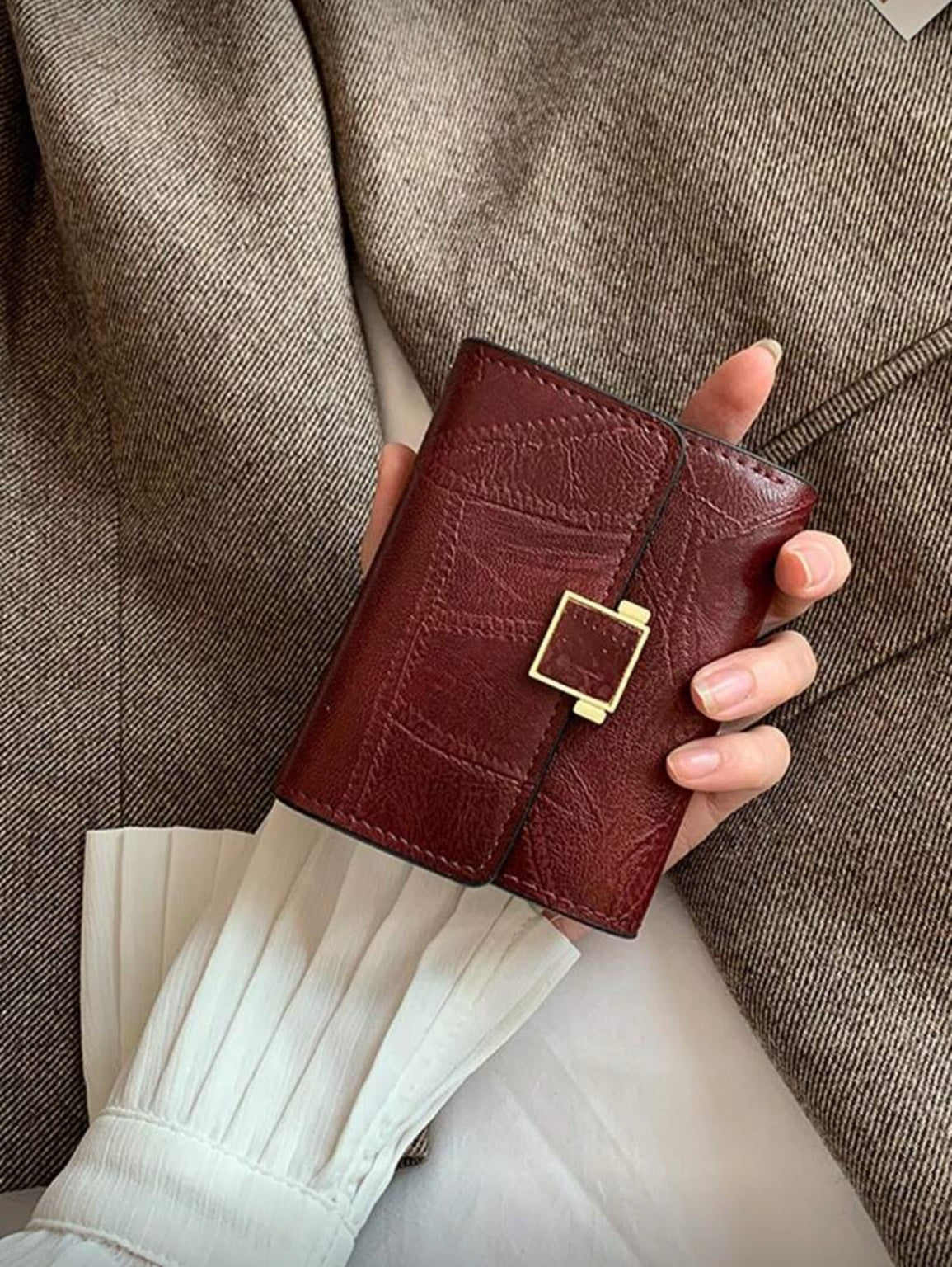 Burgundy buckle compact wallet in hand