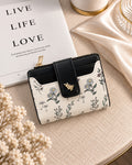 Ivory floral compact wallet with black trim on cream table setting