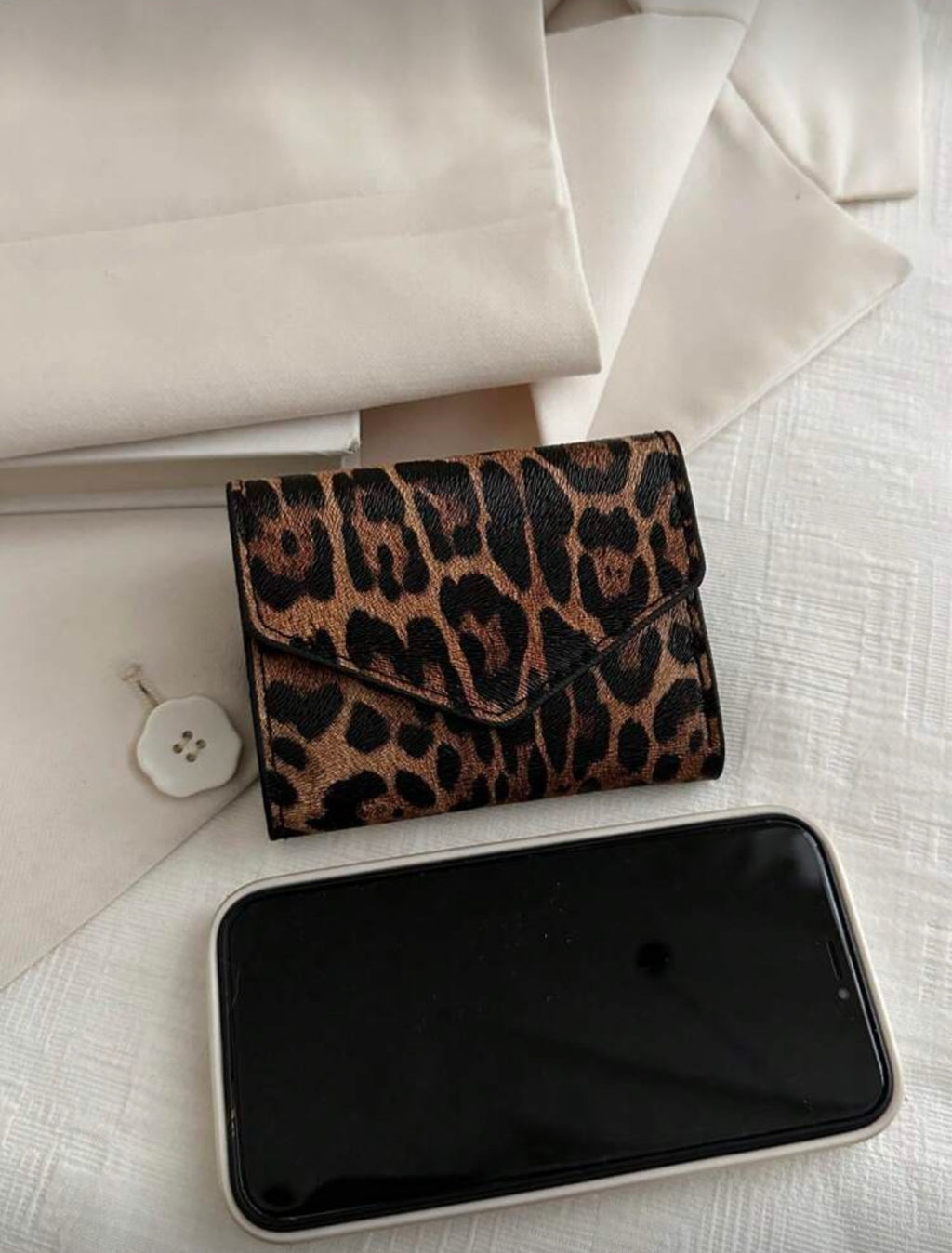 Leopard print envelope wallet shown beside phone for scale