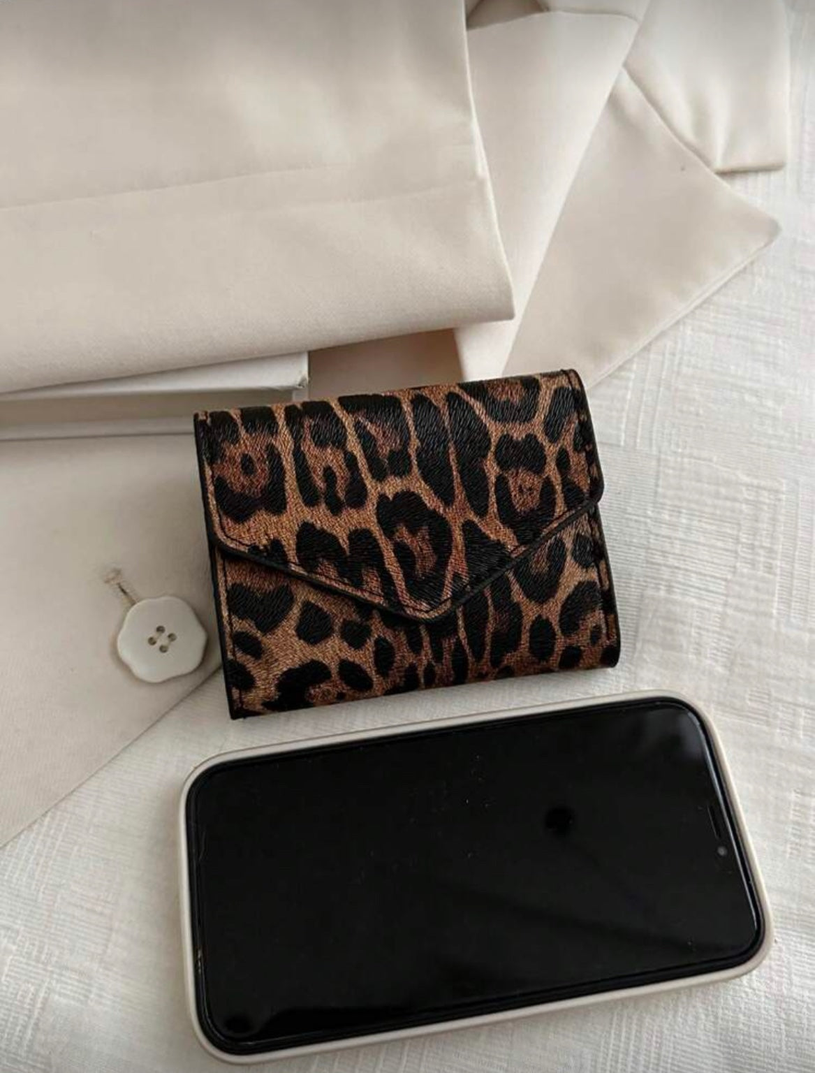 Leopard print envelope wallet shown beside phone for scale