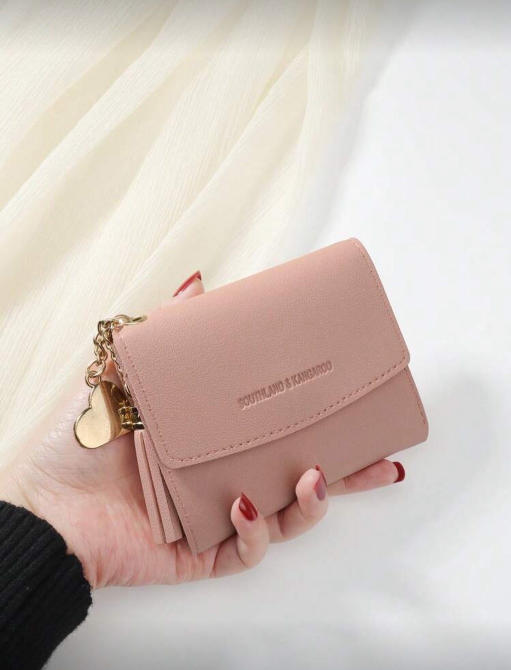 Pink compact wallet with tassel detail view