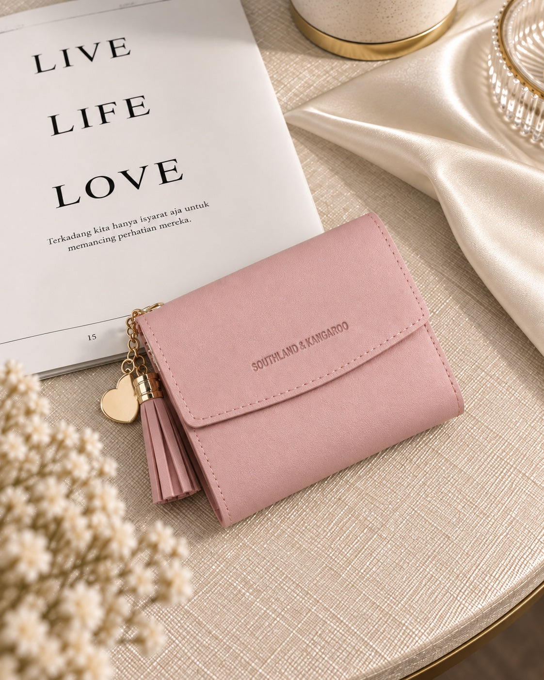 Pink compact wallet with tassel on cream table setting