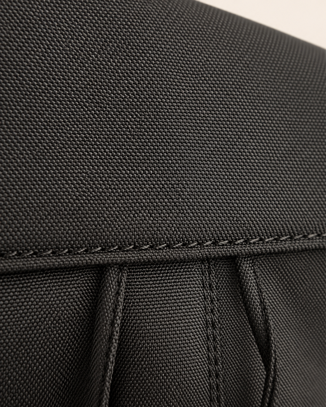 Black backpack woven fabric texture and stitching detail