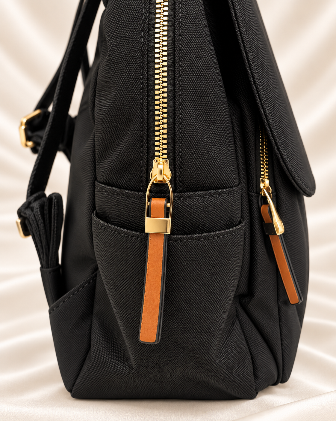 Black backpack side pocket and gold zipper detail