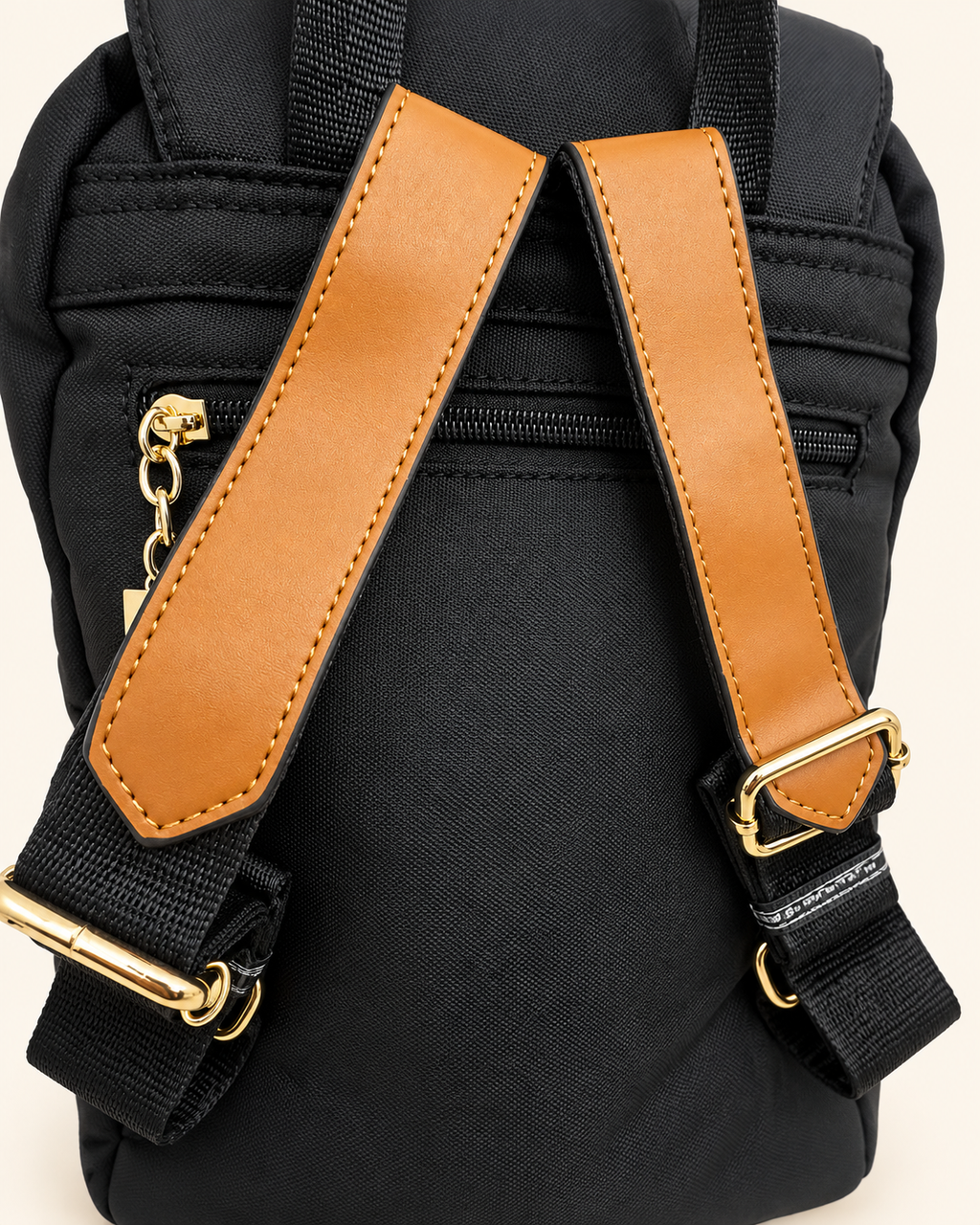 Black backpack shoulder straps and gold hardware detail